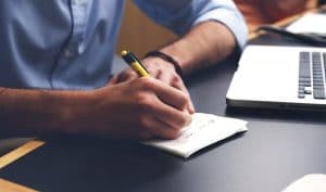 write on pad beside laptop
